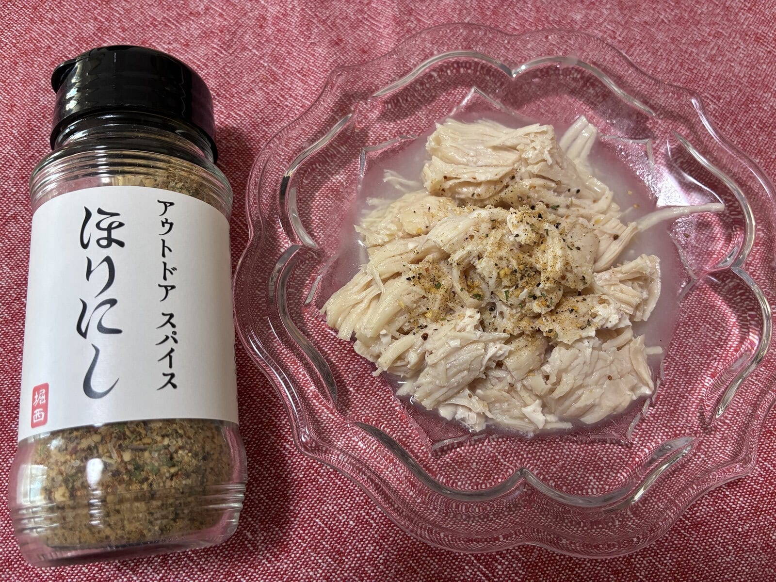 ほりにしの瓶と、ほりにしをかけたほぐしたミート21のサラダチキンを皿に乗せて撮影した写真