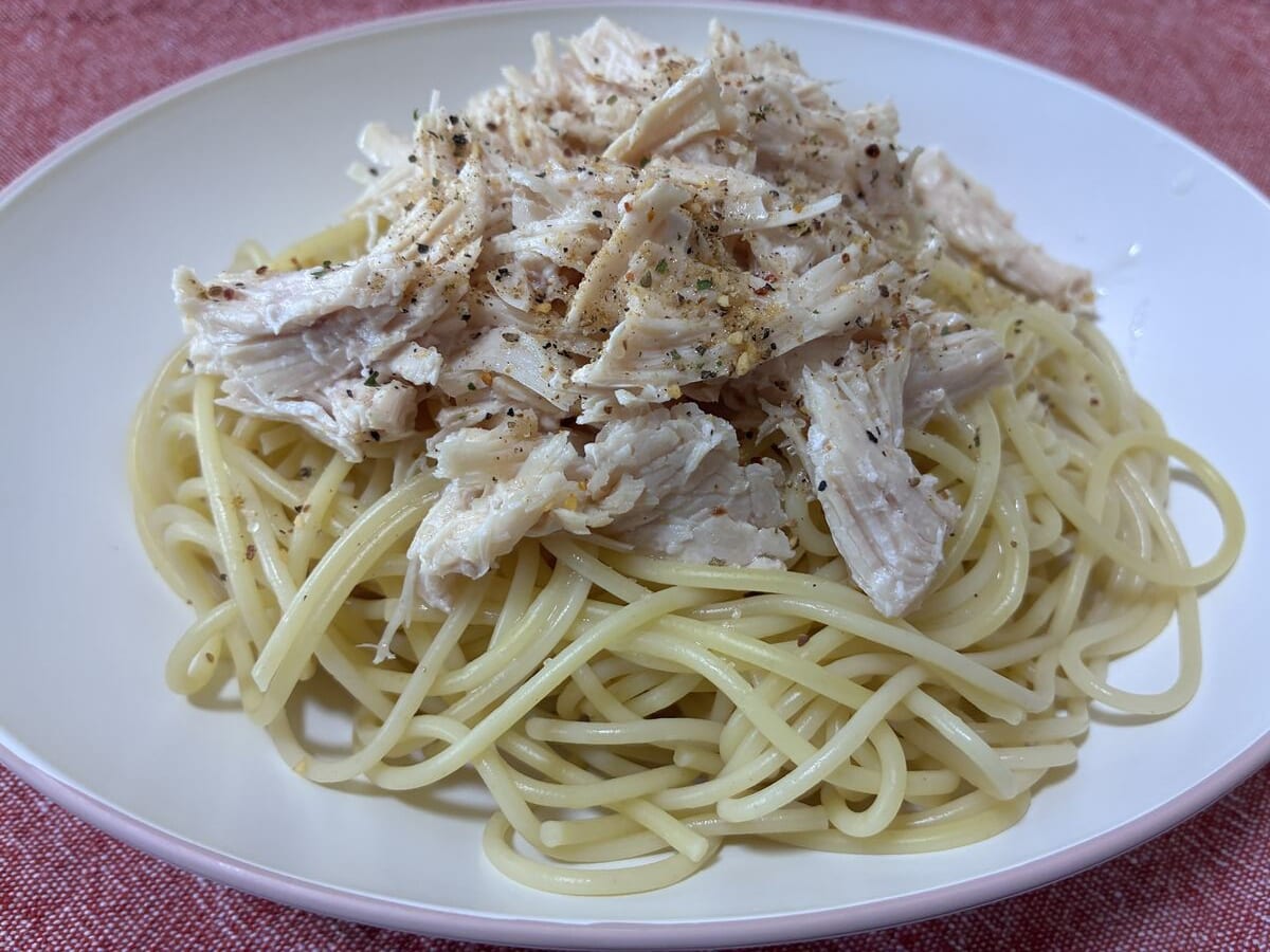 塩ゆでしたパスタにほぐしたミート21のサラダチキンを乗せて皿に盛った写真
